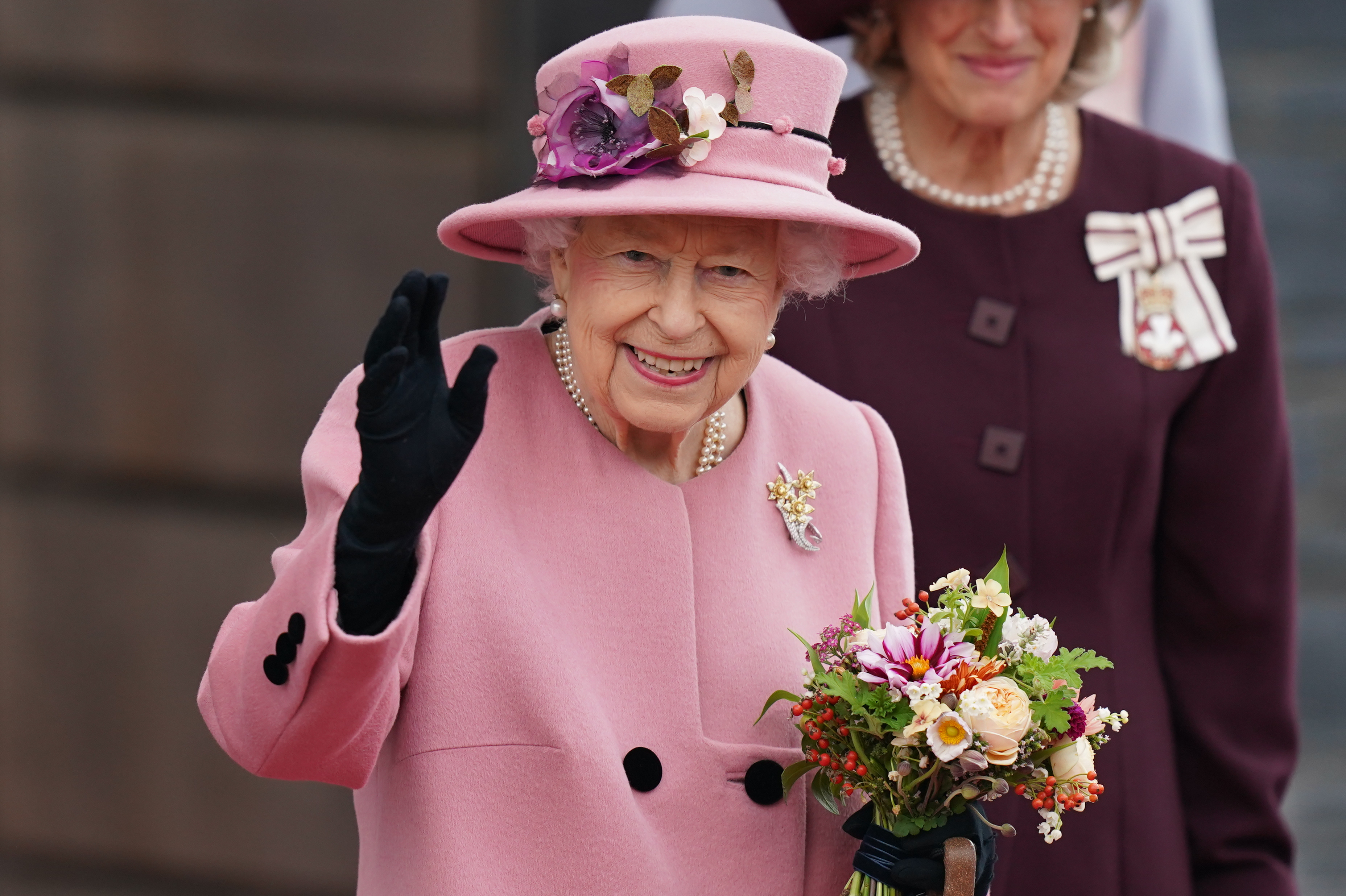 The Queen dressed in pink coat with co-ordinating hat and flowers - photo by Jacob King/PA Wire/PA Images.